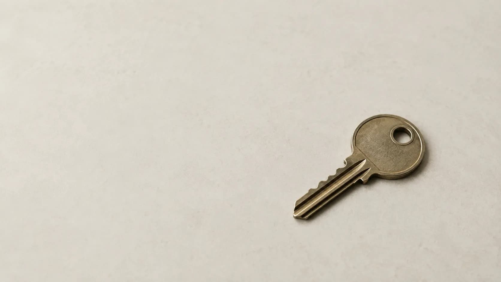 A single key resting on a plain, light-coloured surface